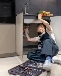 household-repair-middle-aged-man-inspecting-pipe-touching-hand-sink-stylish-modern-kitchen